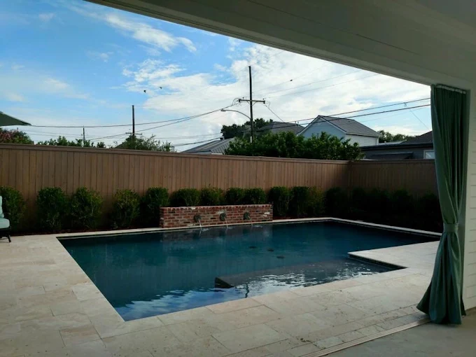 Covered patio view of a rectangular pool with brick water feature