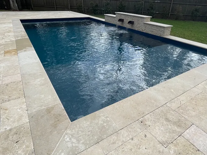 Geometric pool with stacked stone scupper wall and travertine surround