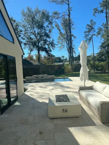 Travertine patio with fire table beside a modern pool