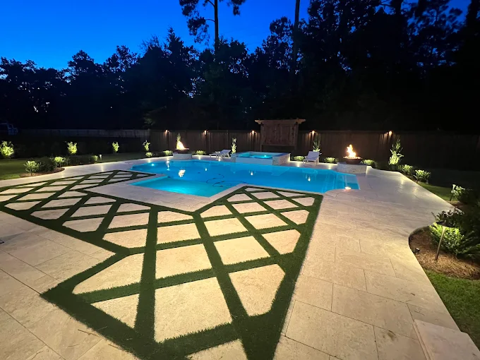 Night-lit pool with fire bowls and turf inlay paver decking