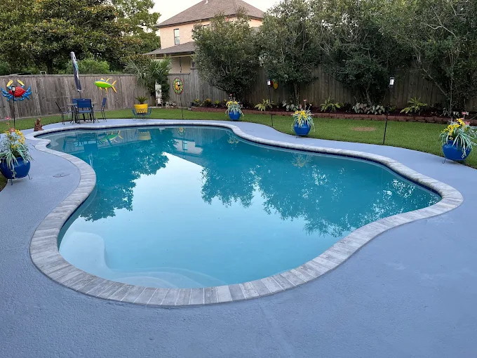 Lagoon-style pool with stamped concrete decking in a private backyard