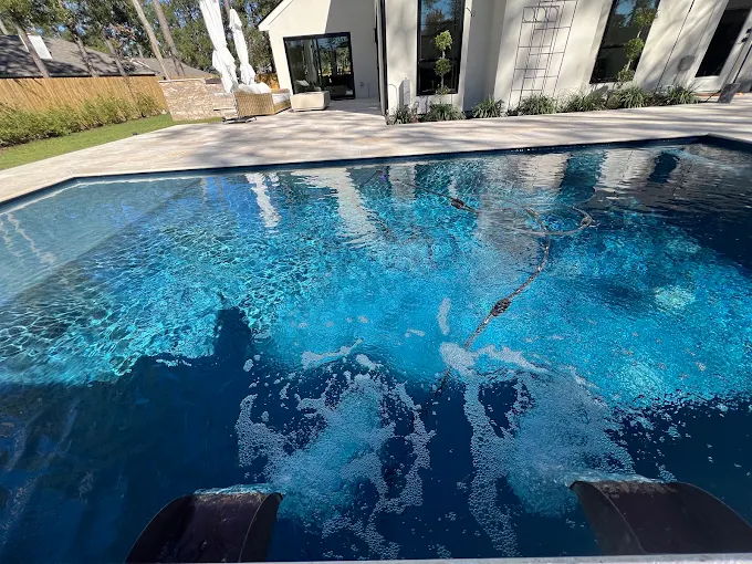 Sun shelf and bubbler jets in a clear blue gunite pool