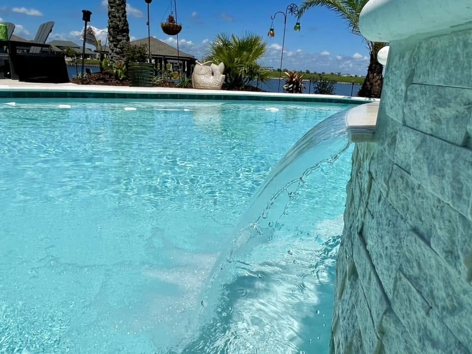 Sheer descent waterfall spilling from a stacked stone spa into a gunite pool