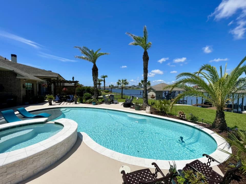 Waterfront freeform pool and raised spa with palm trees on the bayou