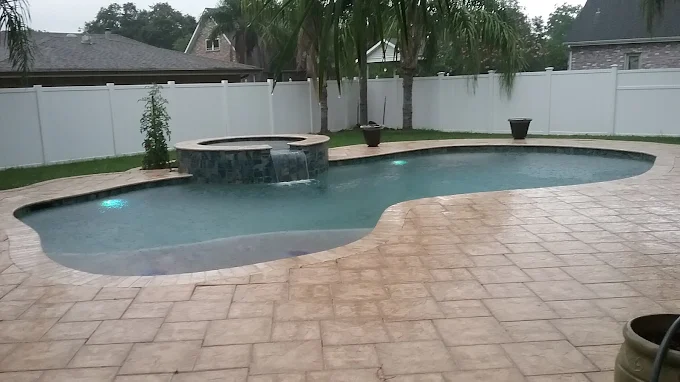 Freeform pool with raised spa spillway and stamped concrete decking