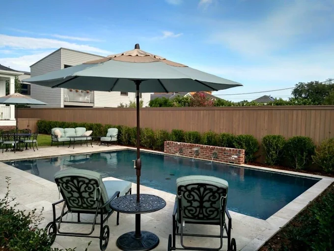 Modern rectangular pool with brick water wall and patio seating