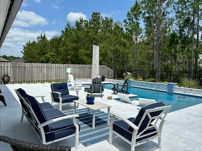 Poolside lounge area with navy furniture and pine tree backdrop