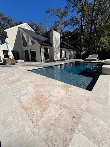 Travertine pool deck and dark-water pool at a modern Louisiana home